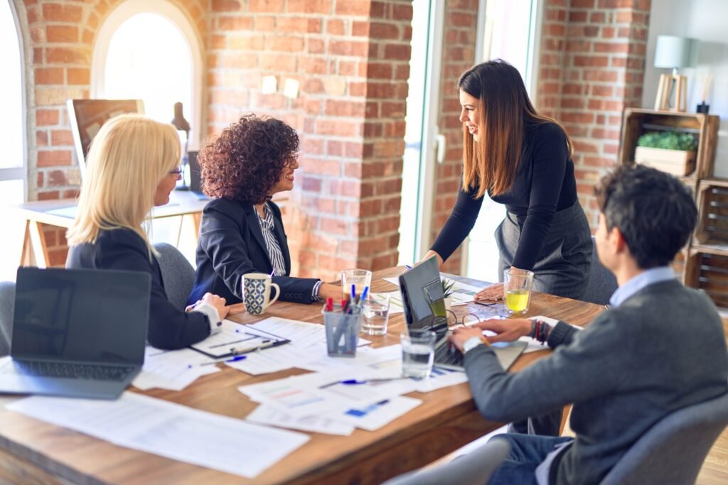 group of business workers smiling happy and confident. working together with smile on face. young beautiful woman standing explaining documents at the office
