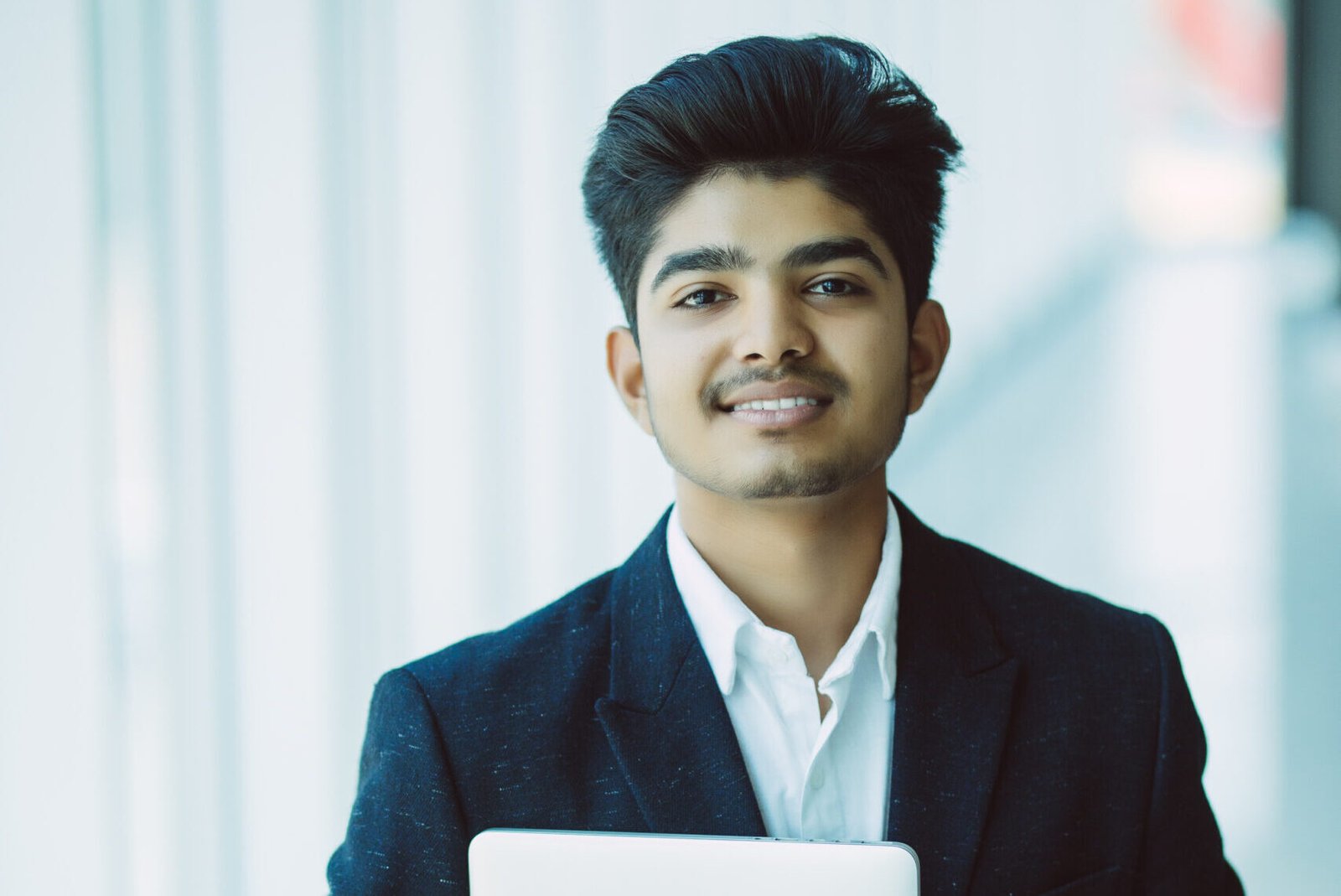 portrait of indian happy businessman using laptop computer in office