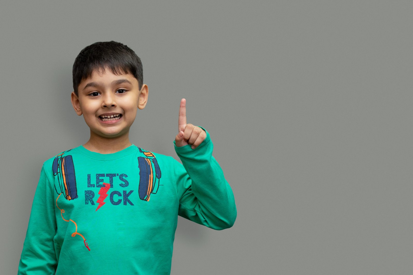 smiling happy boy pointing finger away at copy space isolated over plain background