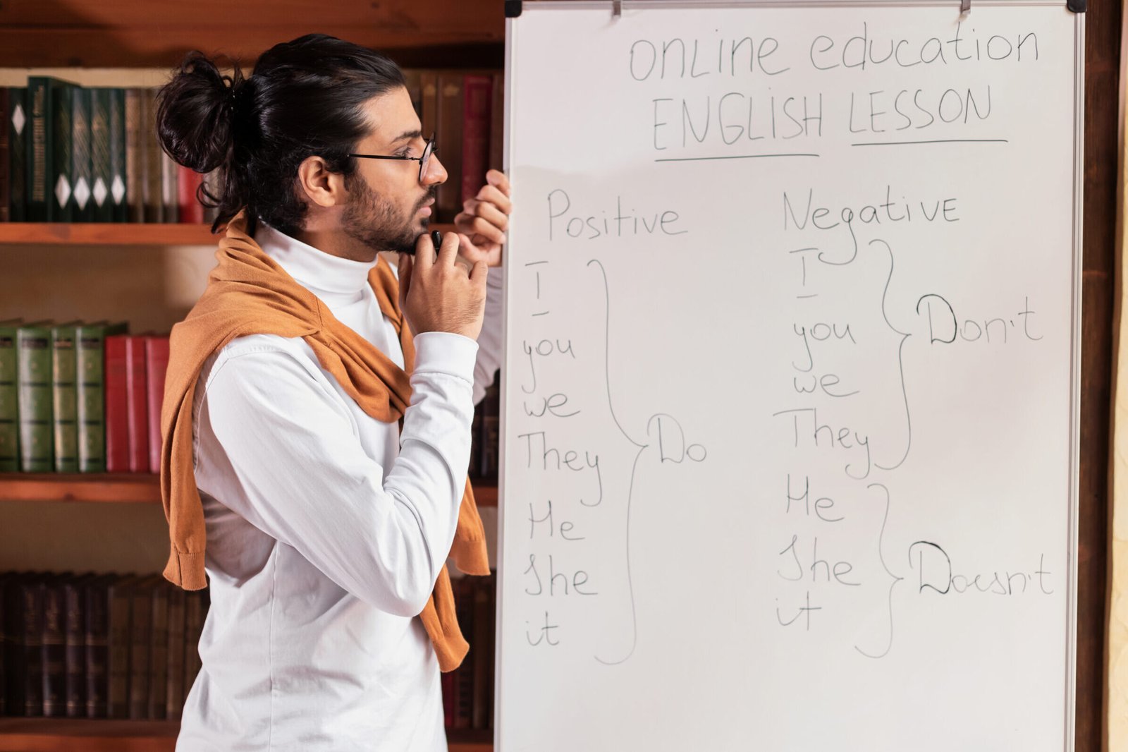 thoughtful indian teacher man standing near blackboard indoor